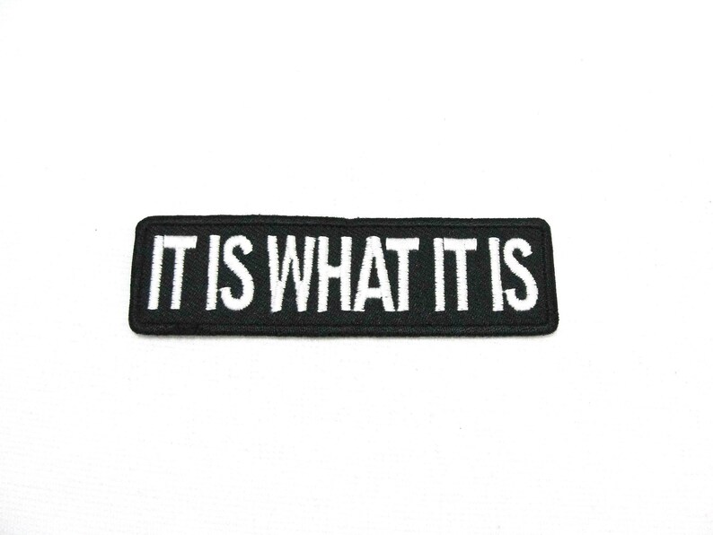 May include: Black embroidered patch with white text that reads "IT IS WHAT IT IS".