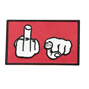 May include: Embroidered patch featuring a red background with a black border. The patch displays two white hand gestures: a middle finger and a fist pointing forward. The design is outlined in black.