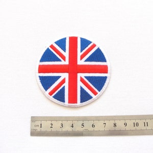 May include: A round, embroidered patch featuring the Union Jack flag in red, white, and blue. The patch is approximately 2 inches in diameter.