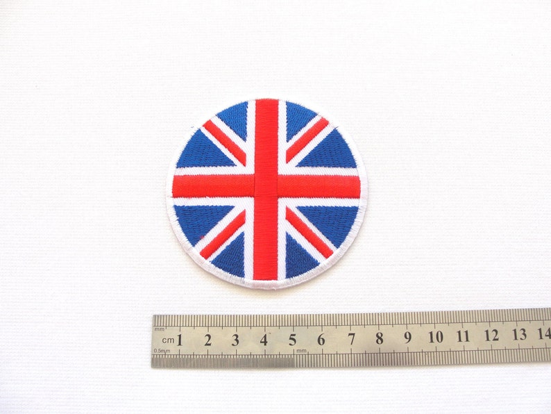 May include: A round, embroidered patch featuring the Union Jack flag in red, white, and blue. The patch is approximately 2 inches in diameter.