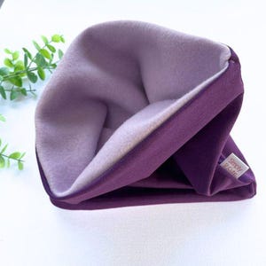 Puede incluir: Gorro de punto de color morado con forro de forro polar, con un dobladillo y el texto "Simply 9 Cute" en el lateral.