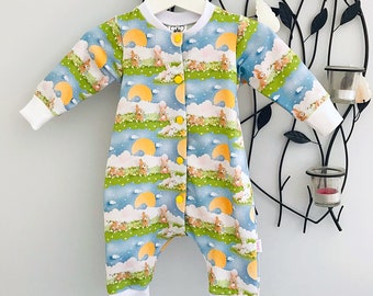May include: A blue and white baby onesie with a yellow button closure. The onesie features a pattern of bunnies and moons on a light blue background.