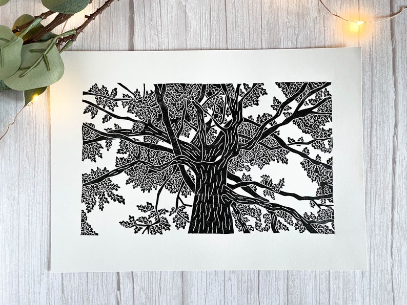 A black lino print of an oak tree. The perspective is from standing underneath the tree looking up to the top of it.