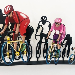 Könnte beinhalten: Eine Wandskulptur aus Metall mit vier Radfahrern auf Fahrrädern. Die Radfahrer sind in Rot, Pink und Schwarz bemalt. Die Skulptur ist auf einem schwarzen Metallsockel montiert.