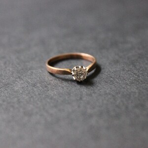 May include: A simple gold band ring with a single round diamond set in a small cluster.