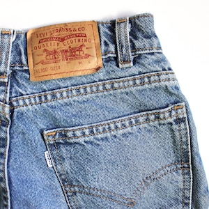 May include: A pair of blue denim jeans with a brown leather patch that reads "Levi Strauss & Co. Original Riveted Quality Clothing" and the number "31350-0214".