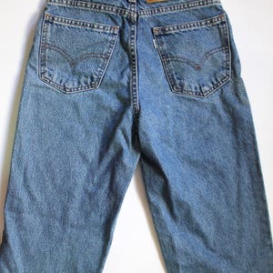 May include: A pair of blue denim jeans with a brown leather Levi's patch on the back waistband.