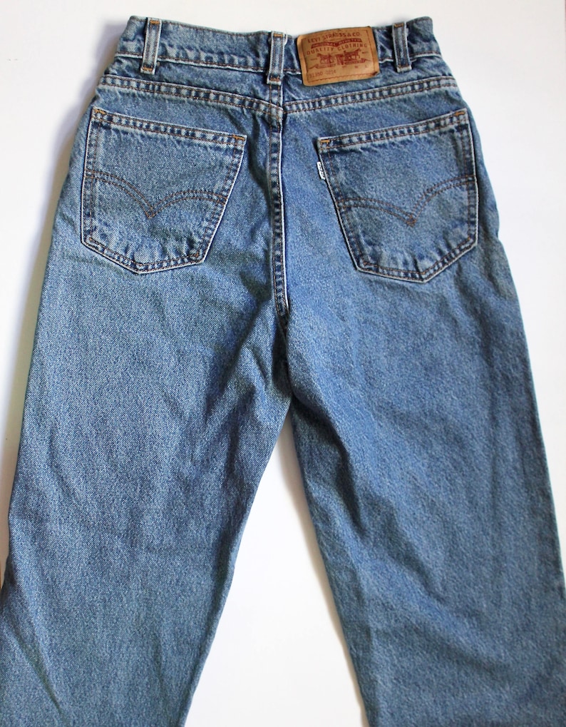 May include: A pair of blue denim jeans with a brown leather Levi's patch on the back waistband.
