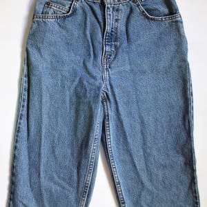 May include: A pair of blue denim jeans with a button fly and five pockets.