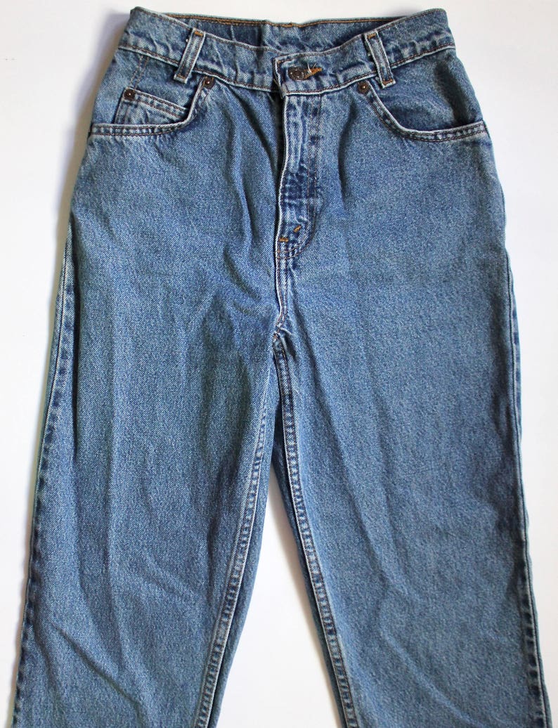 May include: A pair of blue denim jeans with a button fly and five pockets.