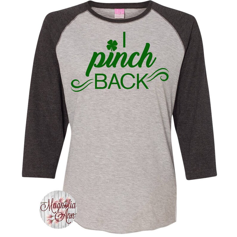 May include: A gray and black baseball tee shirt with a green shamrock and the text "I pinch back" in green.