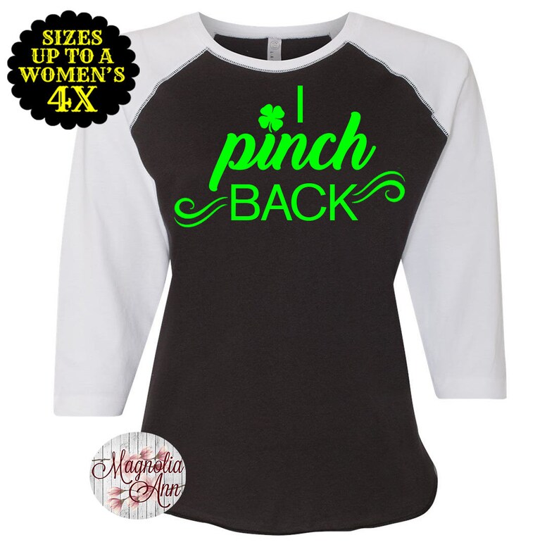 May include: A black and white baseball tee shirt with green text that reads "I pinch back" with a shamrock graphic. The shirt has white sleeves.