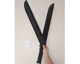 Puede incluir: Dos machetes de plástico negro cruzados en forma de X, sostenidos por una mano.