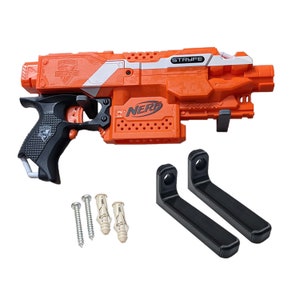 Puede incluir: Un blaster de juguete Nerf Stryfe Elite naranja y negro con una franja blanca y la palabra "STRYFE" impresa en el lateral. El blaster está montado en un soporte de pared negro con dos tornillos.