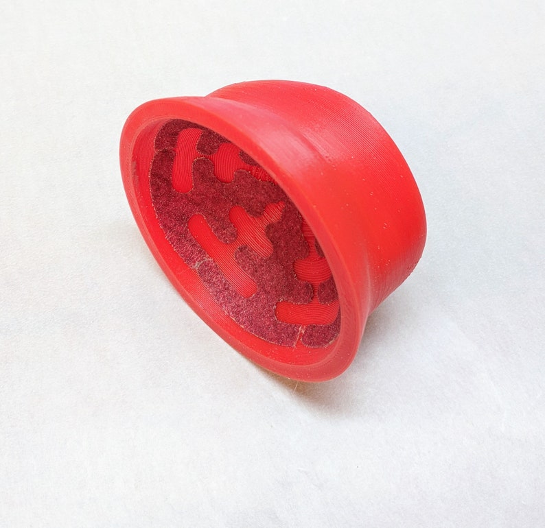 May include: Red plastic lid with a textured, patterned interior. The lid is designed for a container or jar.