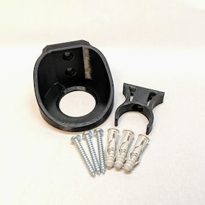 May include: A black plastic wall mount with a circular opening and two screw holes. It comes with three white plastic anchors and three silver screws.