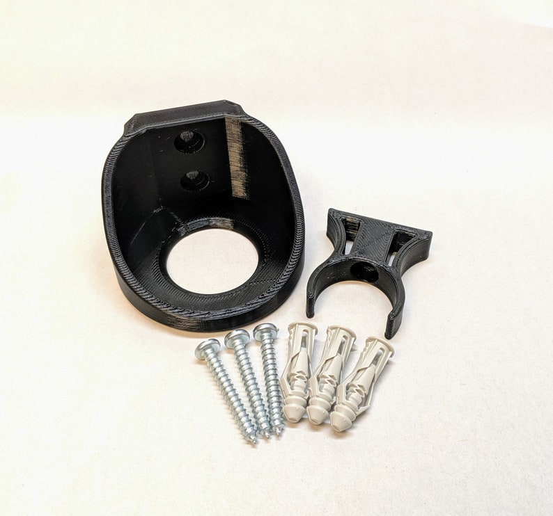 May include: A black plastic wall mount with a circular opening and two screw holes. It comes with three white plastic anchors and three silver screws.