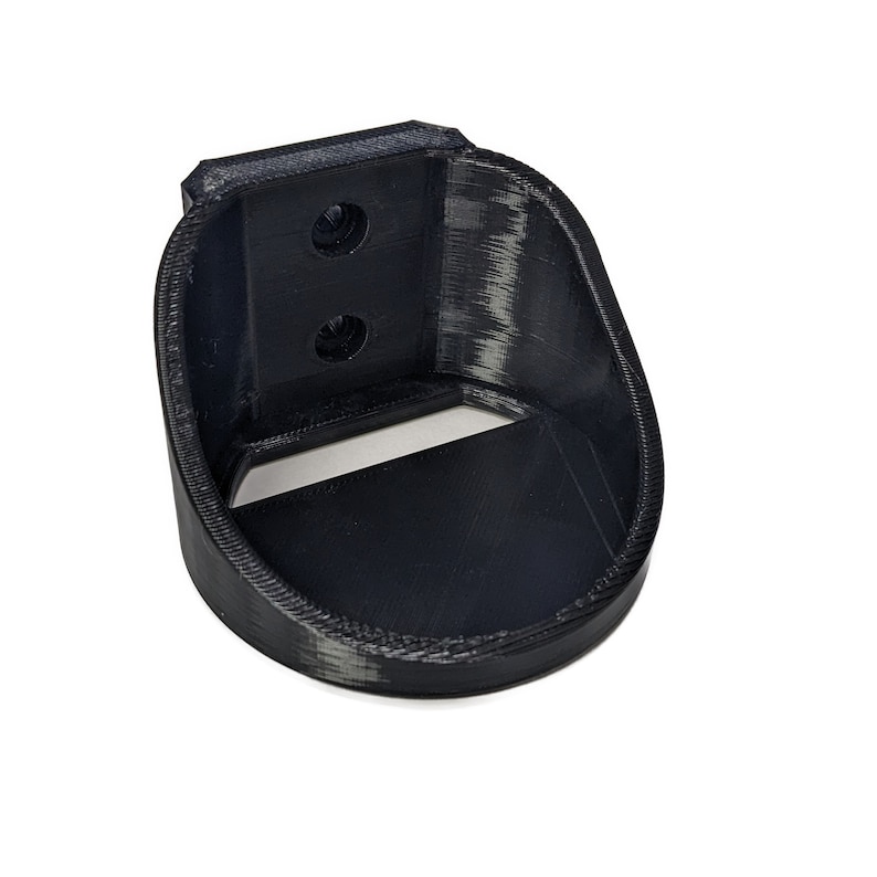 May include: Black plastic wall mount with two screw holes and a curved opening for holding an object.