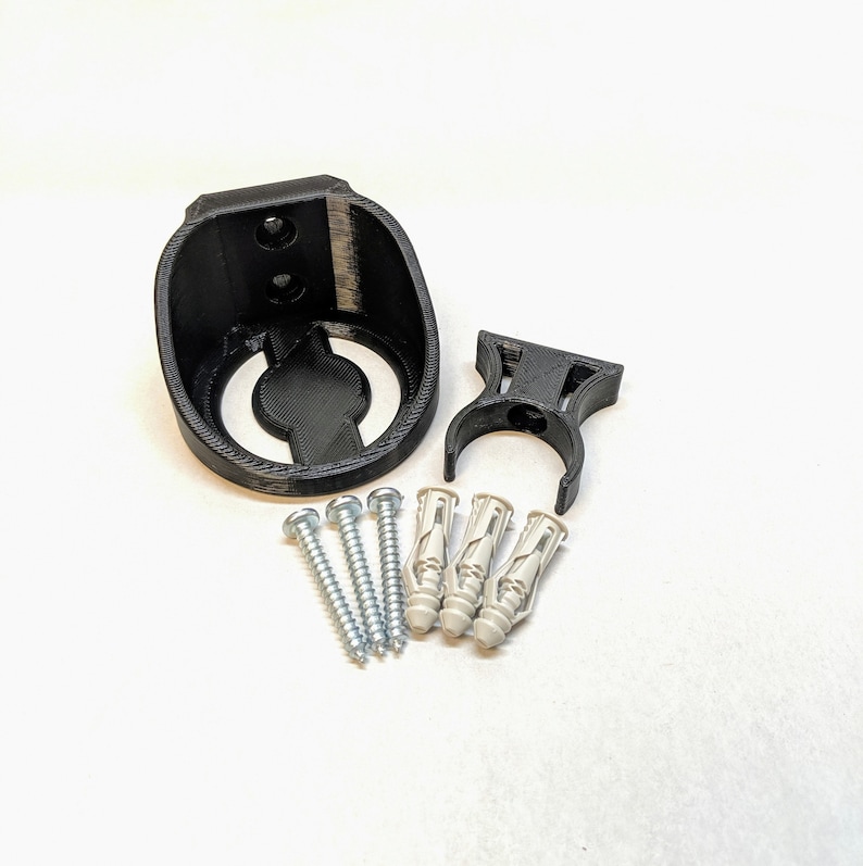 May include: A black plastic wall mount with a circular opening and a separate black plastic hook. The mount comes with four silver screws and four white plastic anchors.