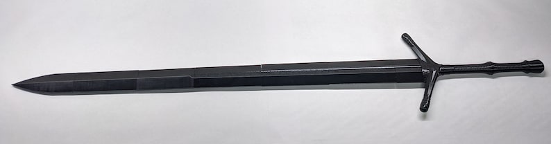 K&ouml;nnte beinhalten: Ein schwarzes Metalls Schwert mit einem Kreuzschutz und einer spitzen Spitze. Das Schwert ist etwa 90 cm lang.