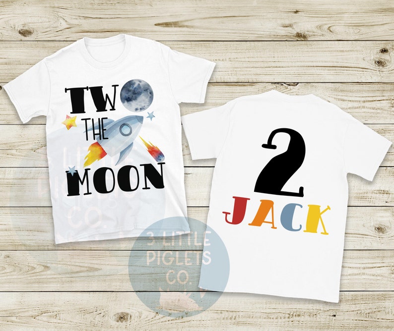 May include: White t-shirt with a rocket ship graphic and the text "TWO THE MOON" on the front. The back of the shirt has a large black number "2" and the name "JACK" in colorful letters. A fun birthday shirt.