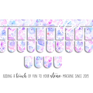May include: Floral-patterned steno machine key covers in shades of purple, blue, and pink. The design features watercolor-style flowers. Text at the bottom reads: "Adding a touch of fun to your steno machine since 2019."