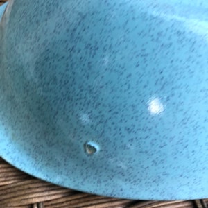 May include: A light blue ceramic bowl with a speckled finish. The bowl has a small chip on the bottom.