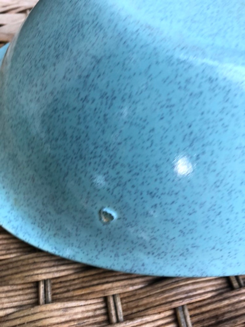 May include: A light blue ceramic bowl with a speckled finish. The bowl has a small chip on the bottom.