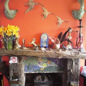 May include: A rustic fireplace mantel with a mosaic tile design and a wood-burning stove. The mantel is decorated with various ceramic birds, a ceramic deer, and other decorative items.