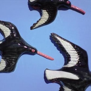 May include: Three black and white ceramic birds with pink beaks. The birds are in flight and have a stylised design.