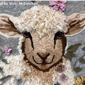 May include: A detailed rug featuring a lamb's face with a fluffy, cream-colored wool head and brown ears. The lamb is surrounded by colorful, felt flowers in shades of pink, yellow, and purple. The text "Hooked by Vicki McCutchan" is at the top.