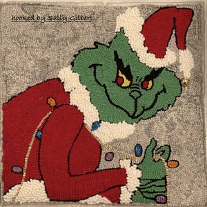 May include: A green Grinch with a red Santa hat is holding a string of colorful lights. The Grinch is smiling mischievously. The background is a gray and white rug. The text "hooked by Sally Gilbert" is in the top left corner of the image.