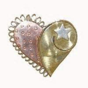 May include: A heart-shaped pendant made of metal with a gold and copper finish. The heart is decorated with a delicate, intricate design and a small star in the centre.