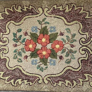 May include: A rectangular rug with a floral design. The rug features a central bouquet of red flowers with yellow centers, surrounded by green leaves and blue accents. The border is a mix of brown and tan.