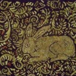 May include: A textile with a rabbit design. The rabbit is depicted in gold and tan hues, set against a dark background with swirling, floral patterns in gold and green. The design has a vintage aesthetic.