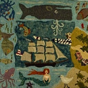 May include: Hand-hooked rug featuring a nautical theme with a ship, whale, mermaid, and various sea creatures. The rug has a blue background with tan, green, and brown accents. The ship has tan sails and a black hull. The rug measures approximately 36 inches by 24 inches.