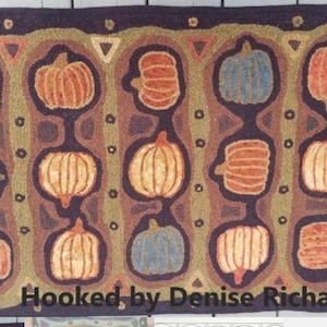 May include: Hand-hooked rug featuring a pattern of pumpkins in shades of orange, blue, and yellow. The pumpkins are set against a dark purple background with brown and green accents. The rug has a rectangular shape and the text "Hooked by Denise Richard" is visible.