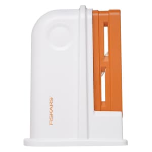 May include: A white and orange Fiskars vegetable spiralizer. The spiralizer has a white body with an orange blade section. The Fiskars logo is printed on the side. The design features a curved top and a rectangular base.