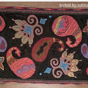 May include: Hand-hooked rug with a black background and a repeating paisley pattern in shades of red, purple, and gold. The rug has a decorative border and the text "hooked by Kathleen Lynch".