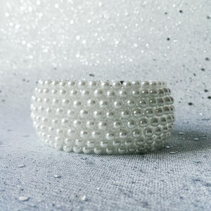 May include: A white pearl headband with a wide band of pearls.