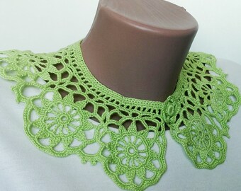 Puede incluir: Un collar de ganchillo verde con un delicado patrón floral. El collar se muestra en un maniquí.