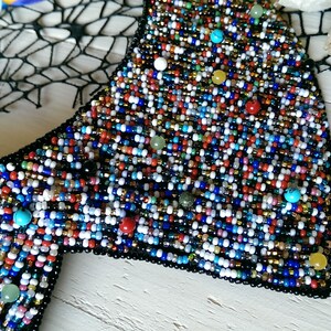 Peut inclure: Un collier ras de cou en perles color&eacute;es avec un dos noir. Les perles sont de diff&eacute;rentes couleurs, notamment rouge, bleu, vert, jaune et blanc.