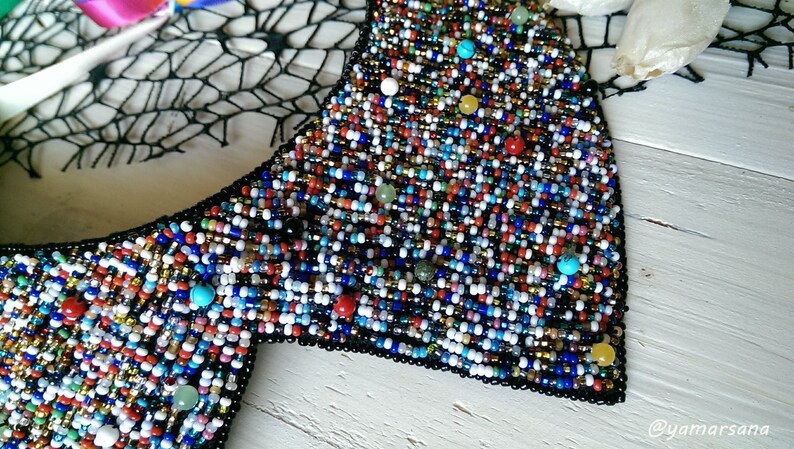 Peut inclure: Un collier ras de cou en perles color&eacute;es avec un dos noir. Les perles sont de diff&eacute;rentes couleurs, notamment rouge, bleu, vert, jaune et blanc.