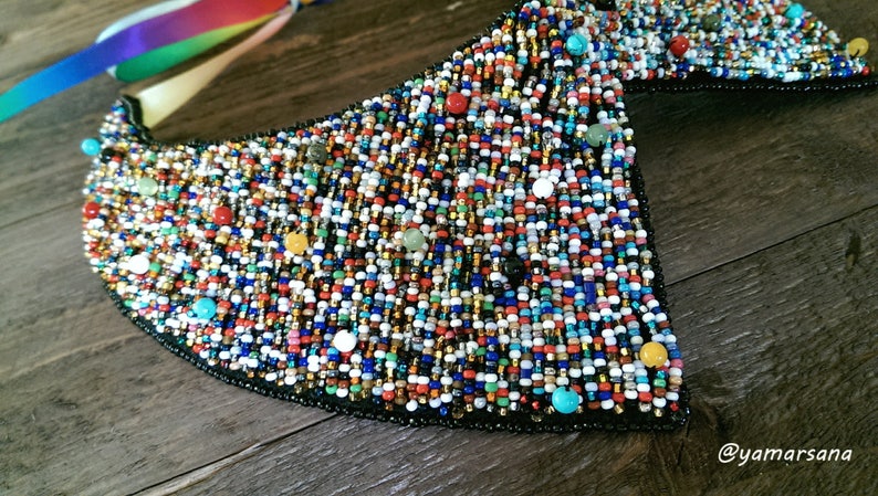 Peut inclure: Un collier de perles color&eacute; avec une vari&eacute;t&eacute; de couleurs, notamment le rouge, le bleu, le vert, le jaune et le blanc. Le collier est fait de petites perles et a une forme triangulaire.