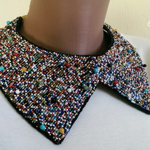 Peut inclure: Un collier de perles color&eacute; avec un dos noir. Les perles sont un m&eacute;lange de petites et de grandes, et elles sont dispos&eacute;es de mani&egrave;re al&eacute;atoire. Le collier est une pi&egrave;ce forte qui ajouterait une touche de fantaisie &agrave; n'importe quelle tenue.