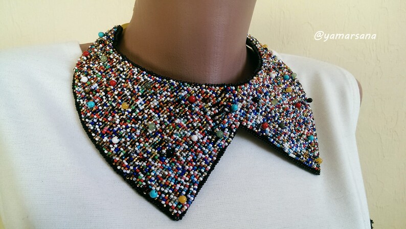 Peut inclure: Un collier de perles color&eacute; avec un dos noir. Les perles sont un m&eacute;lange de petites et de grandes, et elles sont dispos&eacute;es de mani&egrave;re al&eacute;atoire. Le collier est une pi&egrave;ce forte qui ajouterait une touche de fantaisie &agrave; n'importe quelle tenue.