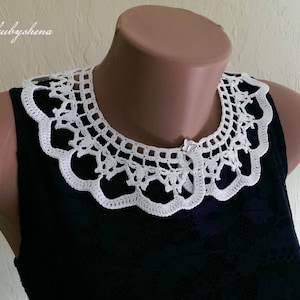 Puede incluir: Un cuello blanco de ganchillo con un borde festoneado y un intrincado dise&ntilde;o calado. El cuello se muestra en un maniqu&iacute; y se combina con una prenda azul oscuro. El texto "Maryna Yakubyshena" es visible.