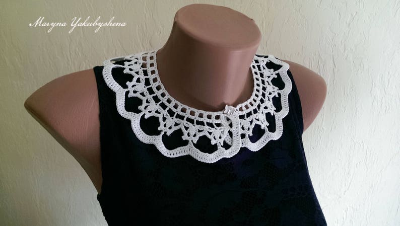 Puede incluir: Un cuello blanco de ganchillo con un borde festoneado y un intrincado dise&ntilde;o calado. El cuello se muestra en un maniqu&iacute; y se combina con una prenda azul oscuro. El texto "Maryna Yakubyshena" es visible.