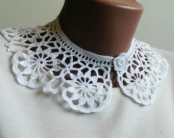 May include: White crocheted collar with a button closure. The collar is made of delicate lace and has a scalloped edge.