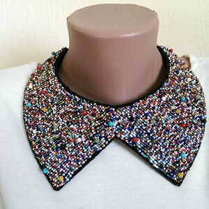 Peut inclure: Une chemise blanche avec un grand col perl&eacute; color&eacute;. Le col est fait de petites perles rondes de diff&eacute;rentes couleurs, notamment bleu, rouge, vert et jaune. Le col est fix&eacute; &agrave; la chemise avec une doublure en tissu noir.